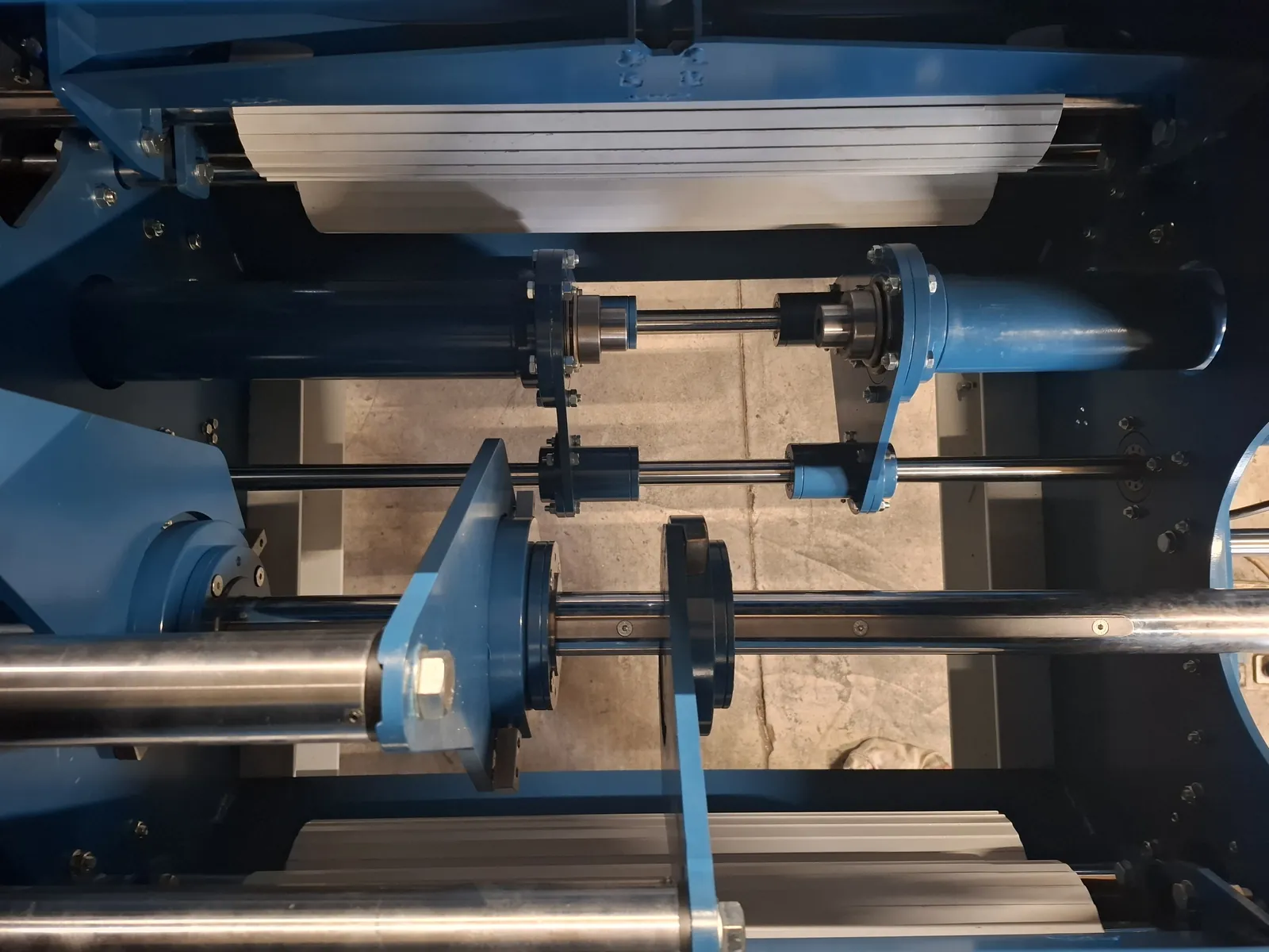 Top view of shafts and blue brackets inside a machine