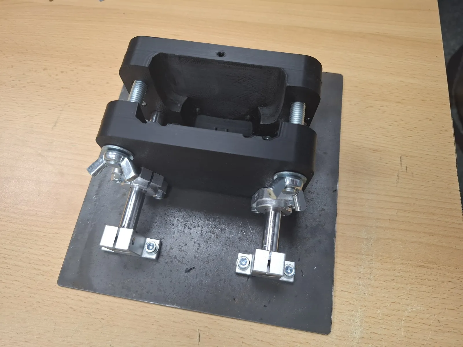 Black fixture with wing screws mounted on a steel plate